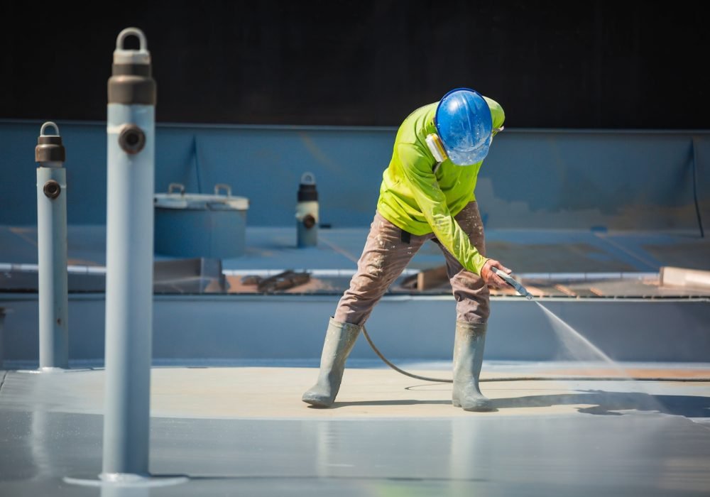 A male worker holding an industrial spray gun used for roof plate tank surface on steel industrial painting and coating.